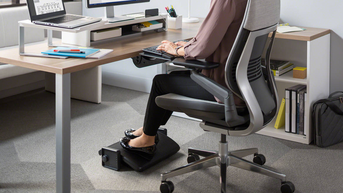 Adjustable ergonomic under desk footrest supporting feet during home office work"