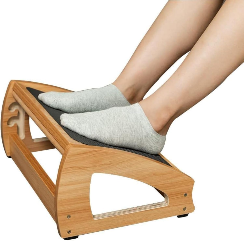 Person resting feet in socks on StrongTek wooden ergonomic footrest under desk