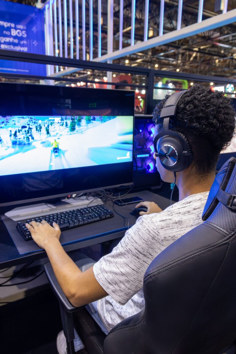 Person sitting in a gaming chair wearing headphones playing a game on a large monitor
