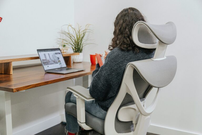 Woman sitting in an ergonomic mesh office chair with adjustable lumbar support at a home office desk with laptop